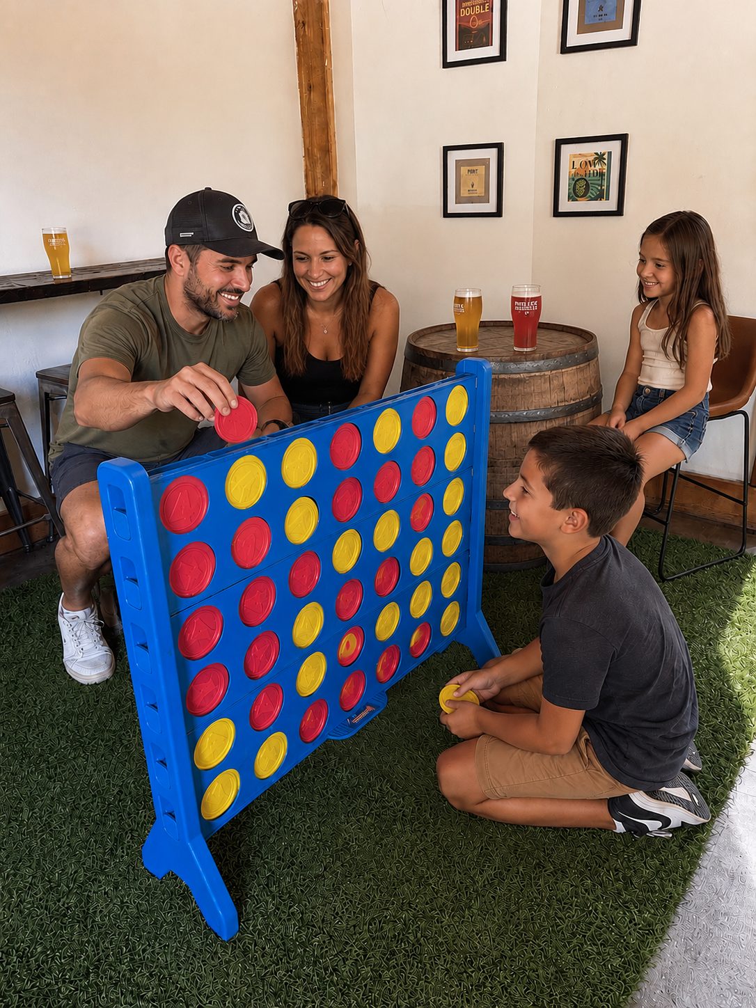 A family playing giant Connect Four at the Prolific taproom, with pints on a barrel table