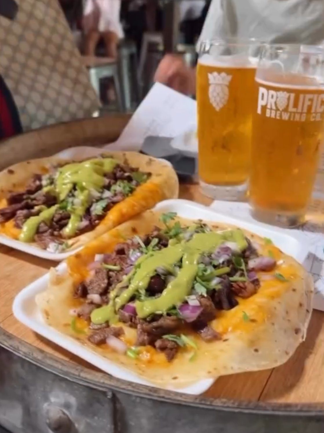 Food truck tacos with two Prolific pints on a barrel-top table